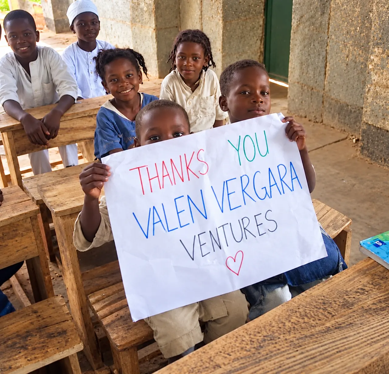 Children in a classroom holding a thank-you sign for Valen Vergara Ventures